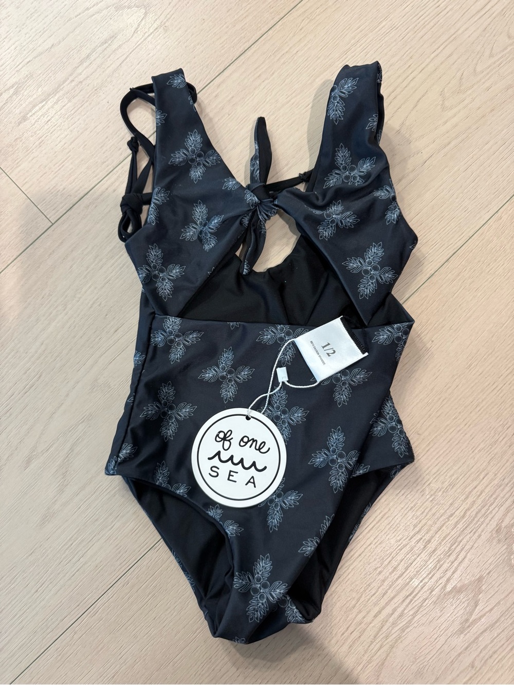 NWT Of One Sea Kids’ Black Floral Tie-Back One-Piece Swimsuit | 1/2